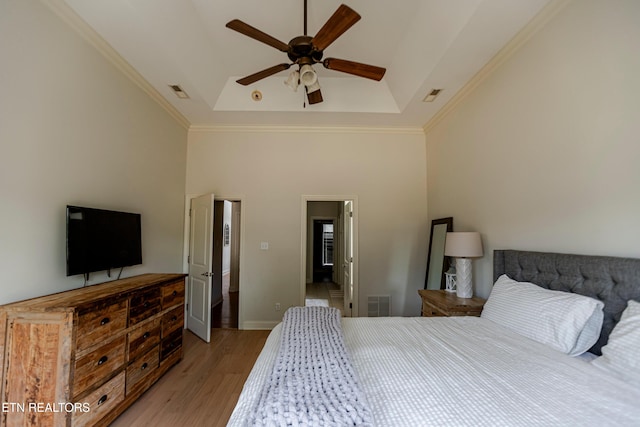 bedroom with a raised ceiling, ornamental molding, a towering ceiling, and light wood-type flooring