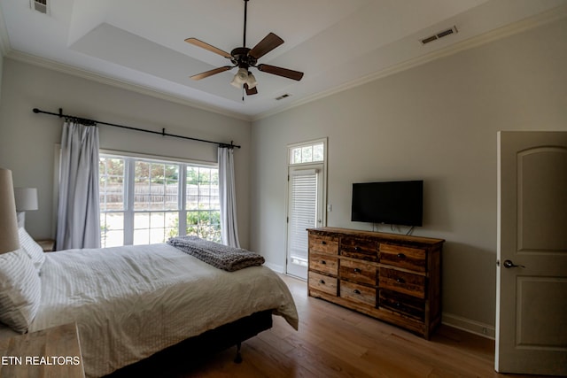 bedroom featuring crown molding, wood-type flooring, a raised ceiling, and ceiling fan