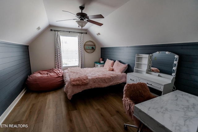 bedroom with dark hardwood / wood-style flooring, lofted ceiling, ceiling fan, and wood walls