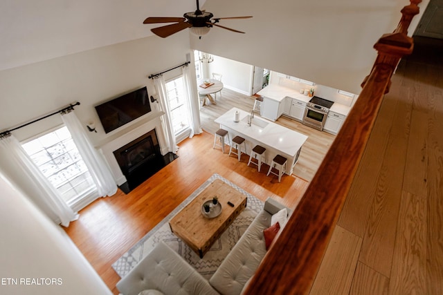 living room with light hardwood / wood-style flooring, high vaulted ceiling, and ceiling fan