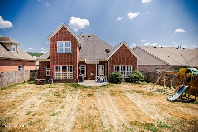 rear view of property featuring a playground, a lawn, and a patio area