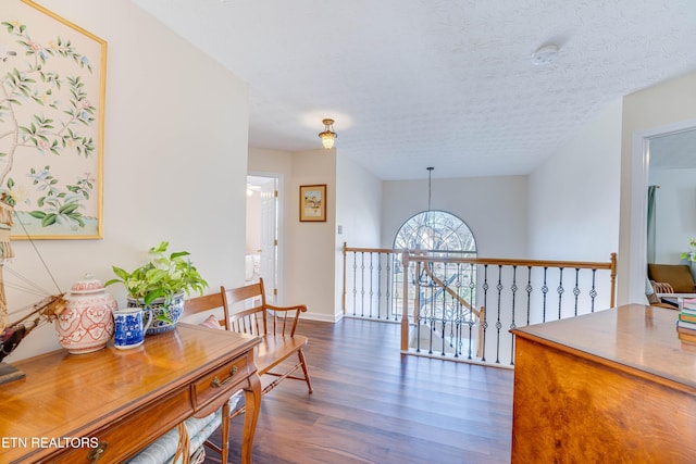 hall featuring a notable chandelier, a textured ceiling, and dark hardwood / wood-style flooring