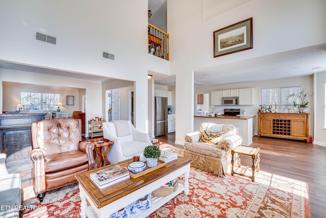 living room with hardwood / wood-style floors, crown molding, and a high ceiling