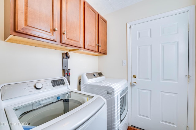 washroom with cabinets, washer and clothes dryer, and a textured ceiling