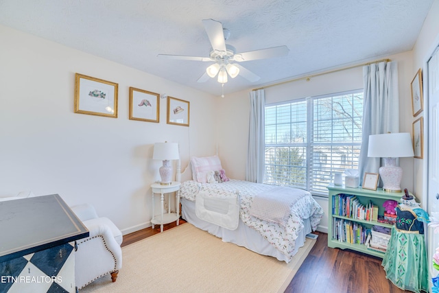 bedroom featuring ceiling fan, dark hardwood / wood-style flooring, and a textured ceiling