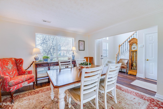 dining room featuring hardwood / wood-style flooring, ornamental molding, a healthy amount of sunlight, and a textured ceiling