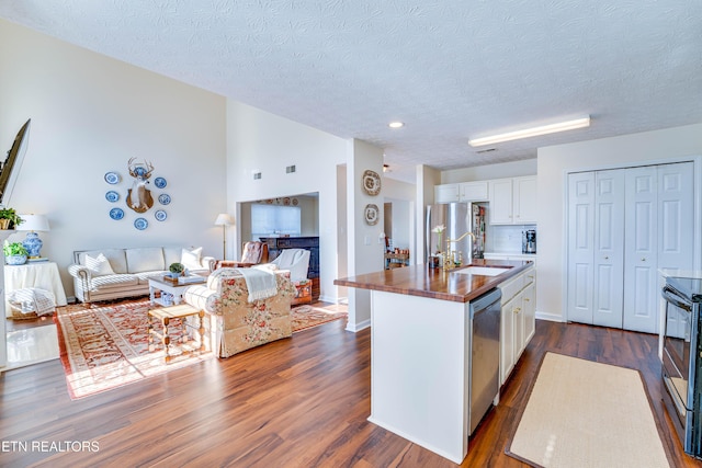 kitchen with sink, stainless steel appliances, dark hardwood / wood-style floors, an island with sink, and white cabinets