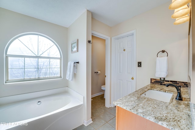 bathroom featuring a bathtub, tile patterned flooring, vanity, toilet, and a textured ceiling