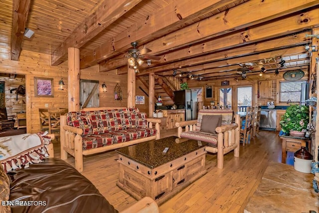 living room featuring wood walls, wood ceiling, light wood-type flooring, ceiling fan, and beam ceiling