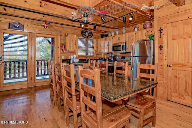 dining room with light hardwood / wood-style flooring, wooden ceiling, beam ceiling, and wood walls