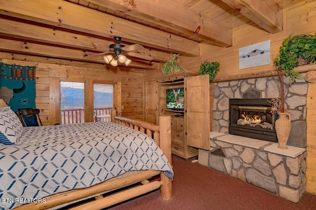 carpeted bedroom featuring beamed ceiling, a fireplace, wood ceiling, and wooden walls