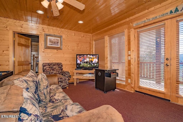 carpeted living room with wood ceiling, ceiling fan, and wood walls