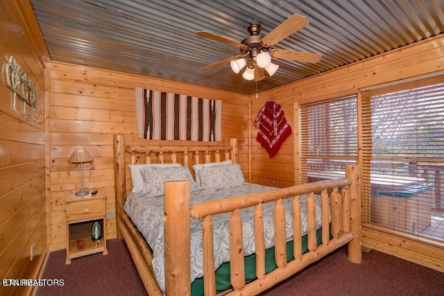 carpeted bedroom with ceiling fan and wood walls