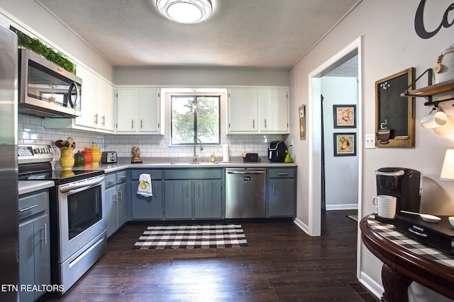 kitchen featuring white cabinetry, appliances with stainless steel finishes, dark wood-type flooring, and sink