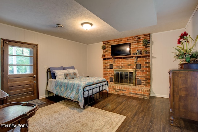 bedroom featuring ornamental molding, dark wood-type flooring, a textured ceiling, and a fireplace