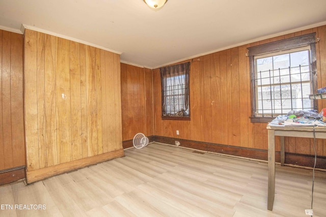 spare room featuring ornamental molding, light hardwood / wood-style floors, and wood walls