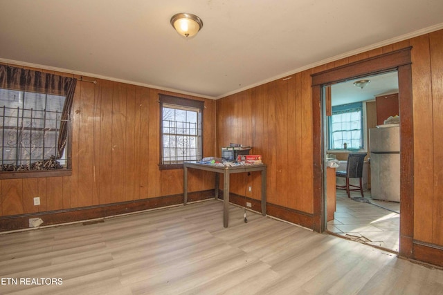 home office featuring crown molding, wooden walls, and light wood-type flooring