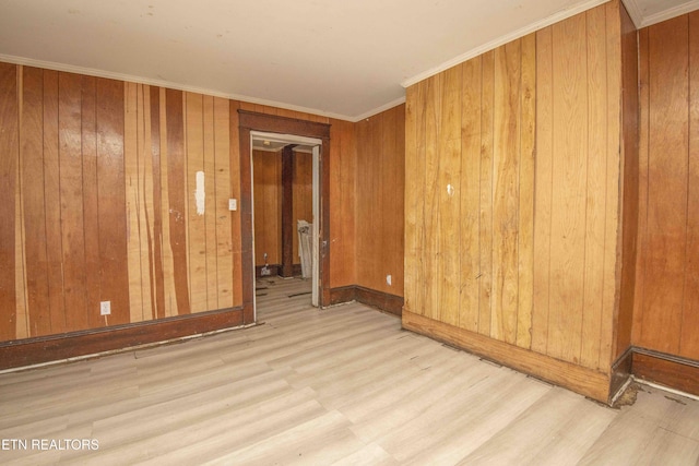 unfurnished room featuring crown molding, light hardwood / wood-style floors, and wood walls