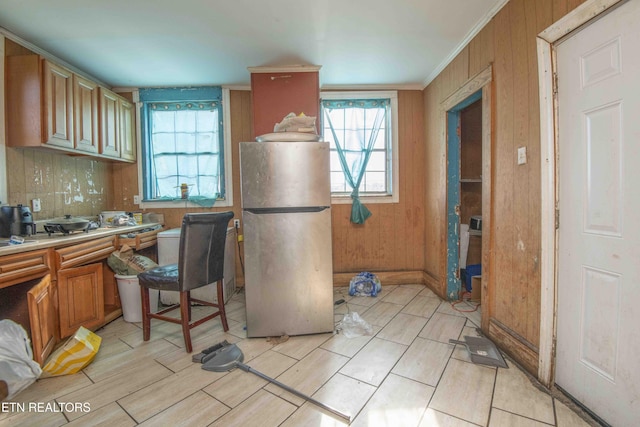 kitchen with crown molding, stainless steel fridge, and wooden walls