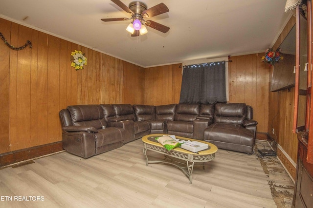 living room featuring crown molding, wood walls, ceiling fan, and light hardwood / wood-style flooring