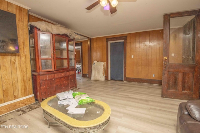 interior space with crown molding, light hardwood / wood-style floors, and wood walls