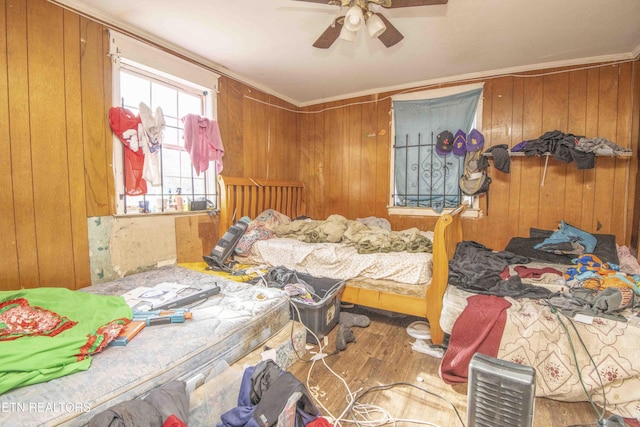 bedroom featuring hardwood / wood-style floors, ornamental molding, ceiling fan, and wood walls