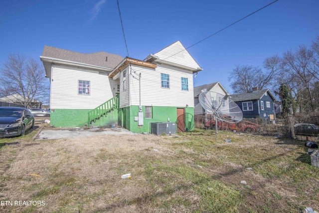 rear view of house featuring central AC and a lawn