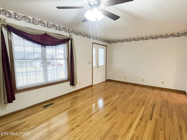 empty room with ceiling fan, wood-type flooring, and a textured ceiling