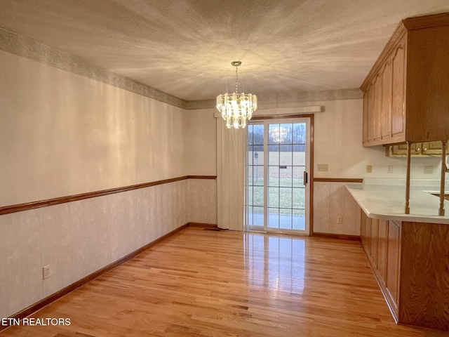 unfurnished dining area featuring a chandelier and light hardwood / wood-style floors