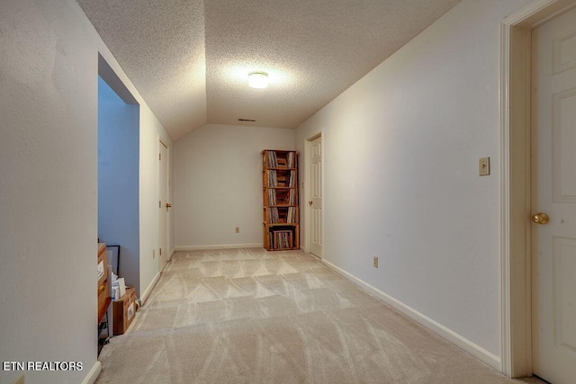 spare room with light carpet, lofted ceiling, and a textured ceiling