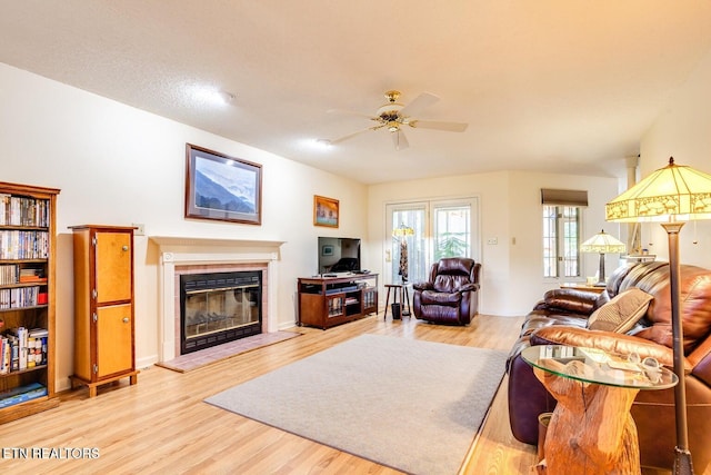 living room with a fireplace, light hardwood / wood-style floors, and ceiling fan