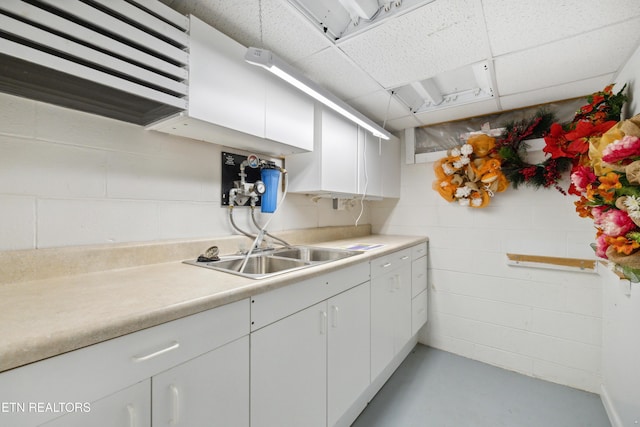 3516 Bluff Point Dr, Knoxville, TN 37920 - kitchen featuring a drop ceiling, concrete block wall, light countertops, white cabinetry, and a sink