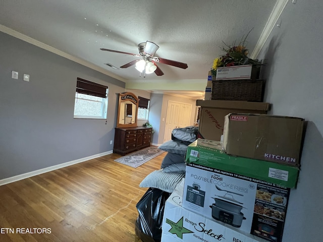 interior space featuring ceiling fan, ornamental molding, wood-type flooring, and a textured ceiling