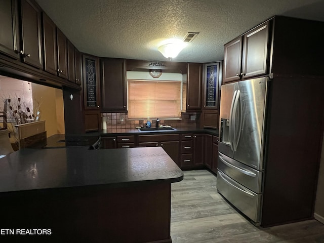 kitchen with dark brown cabinetry, sink, decorative backsplash, and light wood-type flooring