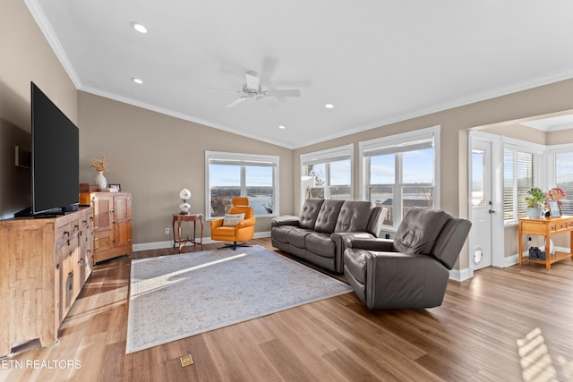 living room with ornamental molding, plenty of natural light, lofted ceiling, and light wood-type flooring