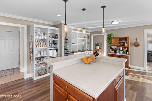 kitchen with hanging light fixtures, ornamental molding, a center island, and dark hardwood / wood-style floors