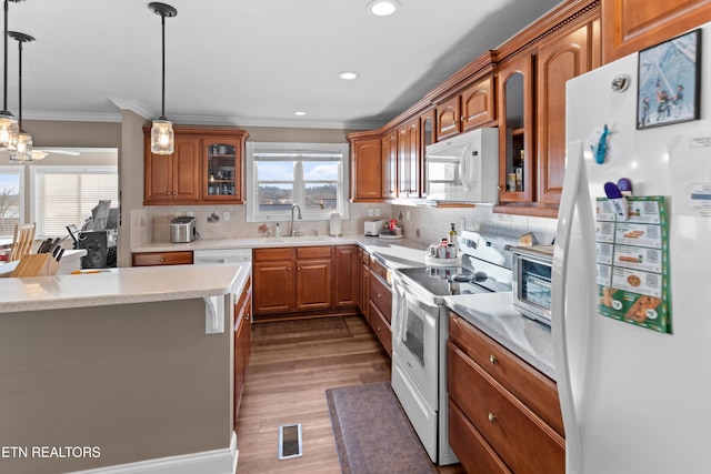 kitchen featuring pendant lighting, sink, white appliances, crown molding, and hardwood / wood-style floors