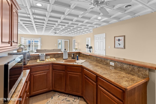 kitchen with ceiling fan, kitchen peninsula, sink, and light tile patterned floors