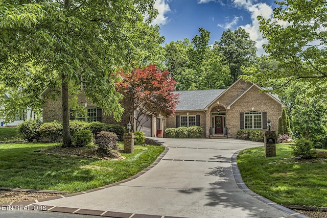 view of front of home featuring brick siding, a front lawn, and driveway
