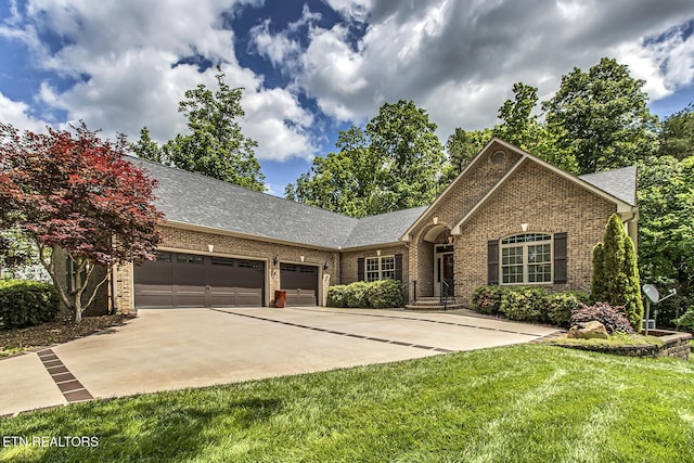 view of front of home featuring brick siding, a garage, driveway, a front lawn, and roof with shingles