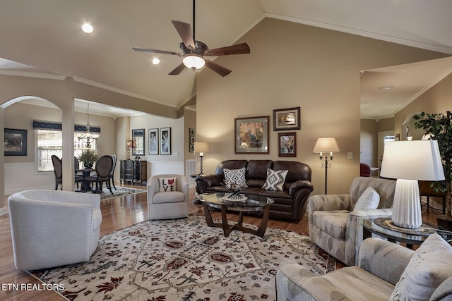 living room with wood finished floors, ornamental molding, arched walkways, a ceiling fan, and lofted ceiling