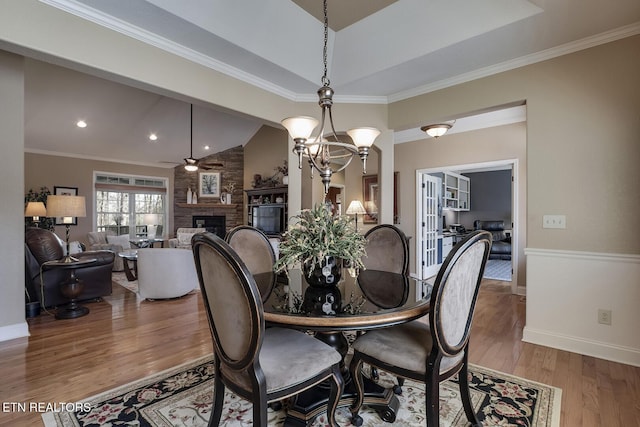 dining space featuring a fireplace, wood finished floors, baseboards, lofted ceiling, and recessed lighting