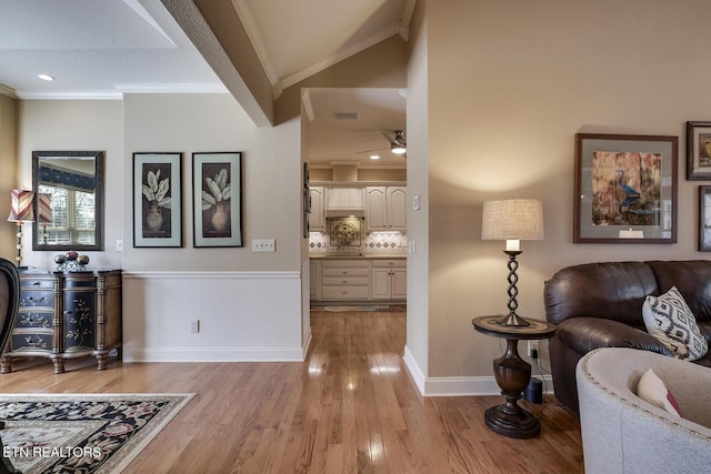 foyer with crown molding, light wood finished floors, lofted ceiling, a ceiling fan, and baseboards