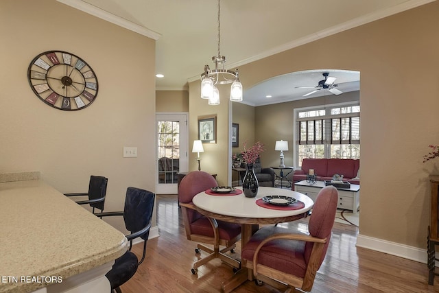 dining space with baseboards, crown molding, wood finished floors, healthy amount of natural light, and a ceiling fan