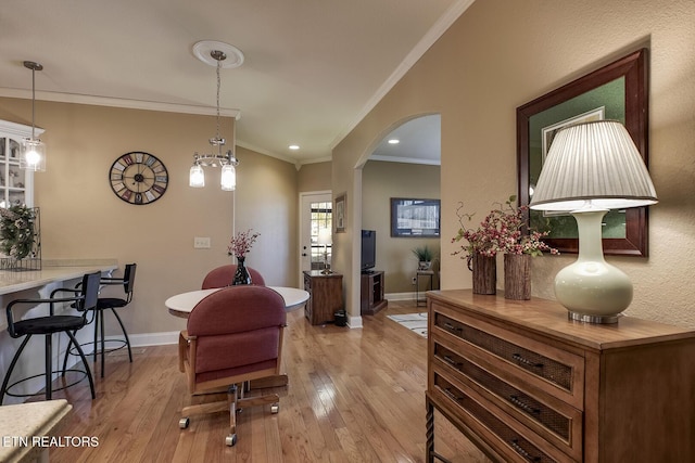 sitting room featuring ornamental molding, lofted ceiling, arched walkways, light wood-style flooring, and baseboards