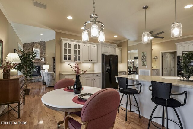 dining room with crown molding, a fireplace, light wood finished floors, ceiling fan, and lofted ceiling
