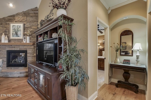 hall featuring wood finished floors, crown molding, baseboards, and lofted ceiling