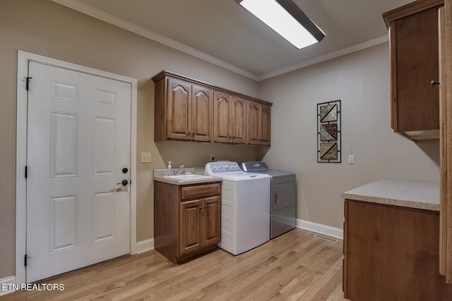 clothes washing area with cabinet space, washer and clothes dryer, ornamental molding, light wood-type flooring, and baseboards