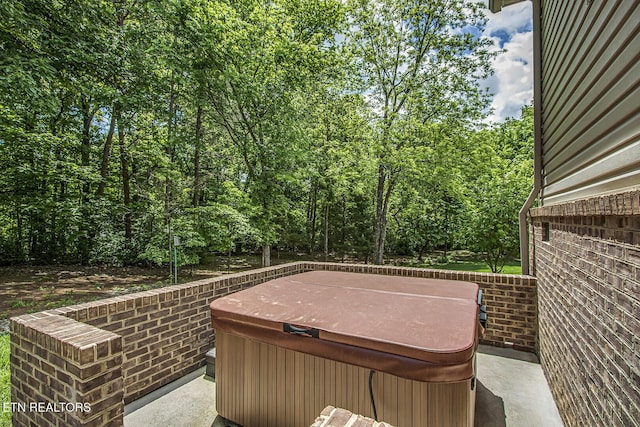 view of patio featuring a hot tub and a wooded view