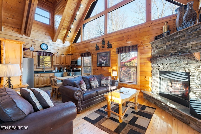 living room featuring sink, light hardwood / wood-style flooring, wooden walls, a skylight, and a stone fireplace